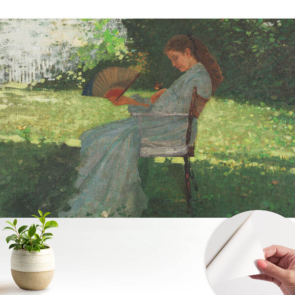 O femeie cu un ventilator în grădină simte armonie